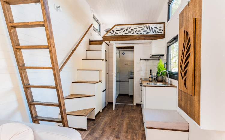 Wnętrze domku Tiny House z widokiem na łazienkę, kuchnię i schody prowadzące na antresolę