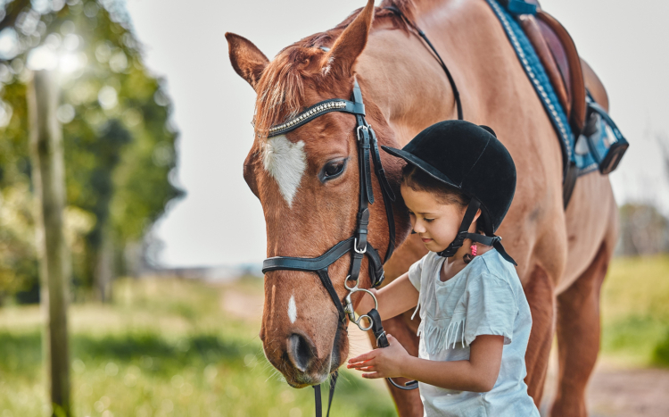 dziewczynka w toczku prowadząca konia