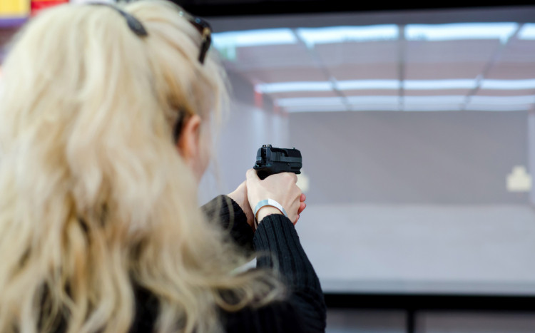 Kobieta w blond łosach celuje pistoletem