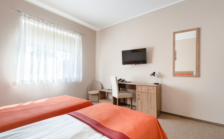 Pokój dwuosobowy z biało-pomarańczowymi łóżkami dla gości