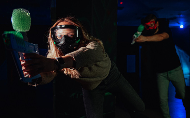 Dziewczyna w masce z pistoletem Gel Blaster podczas rozgrywki w żelowy paintball