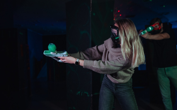 Dziewczyna w masce z postoletem Gel Blaster celująca podczas rozgrywki w żelowy paintball