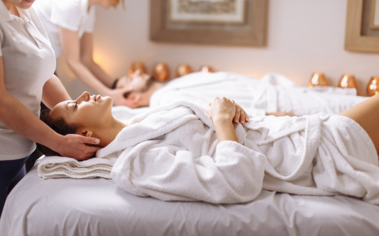 Kobieta i mężczyzna leżący w szlafrokach na plecach podczas wspólnego masażu głowy