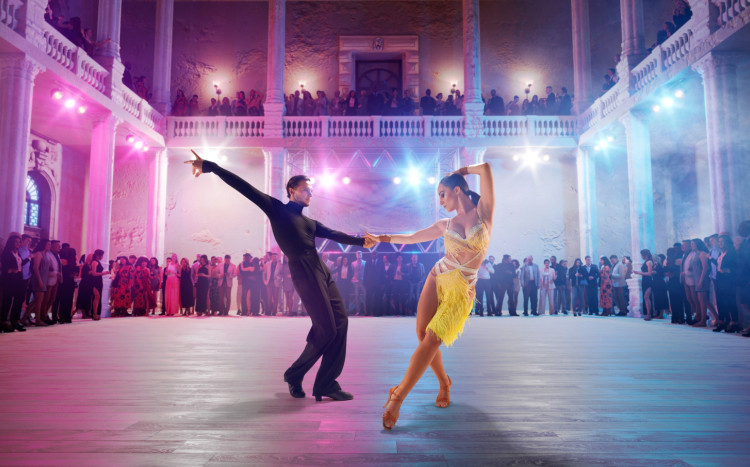 Mężczyzna w garniturze i kobieta w żółtej sukience tańczący taniec latynoamerykański