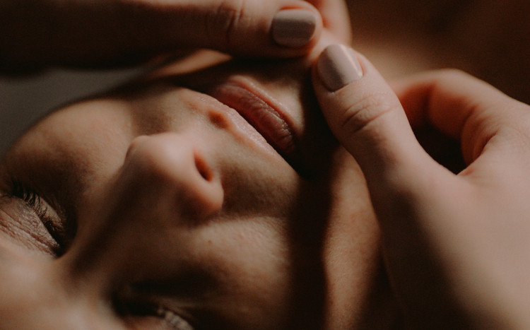 Dłonie masujące brodę kobiety podczas masażu Kobido