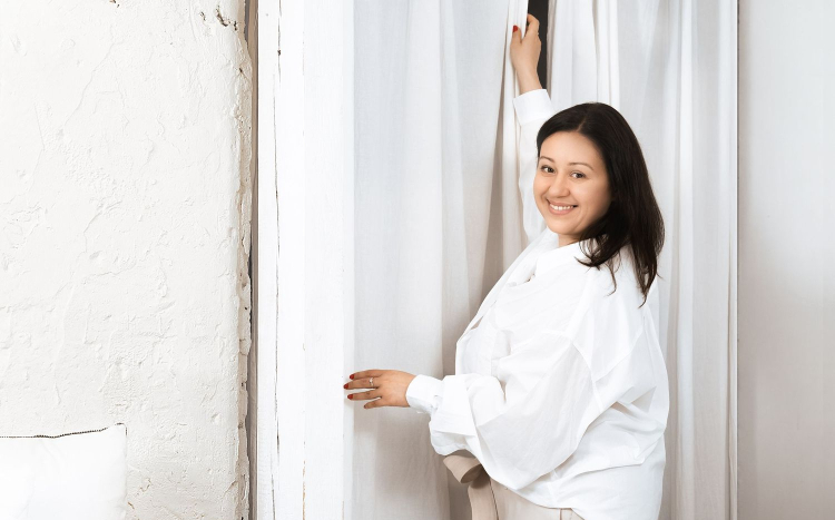Kobieta w białej koszuli z radością przedstawia na zdjęciu zasłony