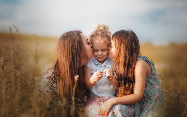 Mama i dwie córki pozujące na łące do wspólnego zdjęcia