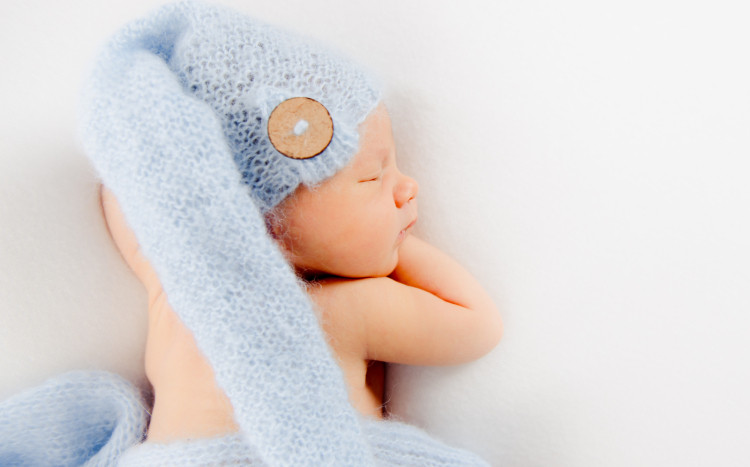 śpiący noworodek w niebieskiej czapeczce