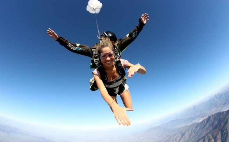 Uśmiechnięta kobieta skacze ze spadochronem