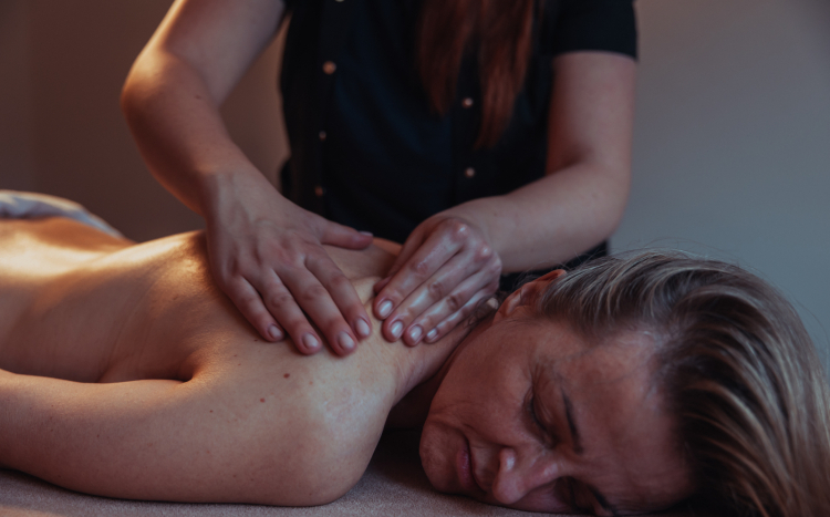 Kobieta leżąca na brzuchu podczas masażu pleców, który polega na uciskaniu i ugniataniu skóry