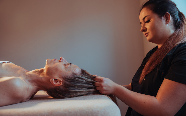 Kobieta podczas masażu głowy, który polega na napinaniu skóry poprzez ciągnięcie włosów