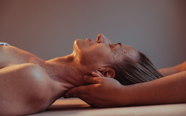 Kobieta leżąca na plecach podczas masażu karku w SPA