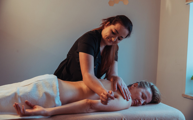 Kobieta leżąca na brzuchu podczas masażu pleców, który polega na ugniataniu łokciem