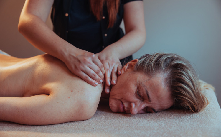 Kobieta leżąca na brzuchu podczas masażu pleców, który polega na uciskaniu i ugniataniu skóry