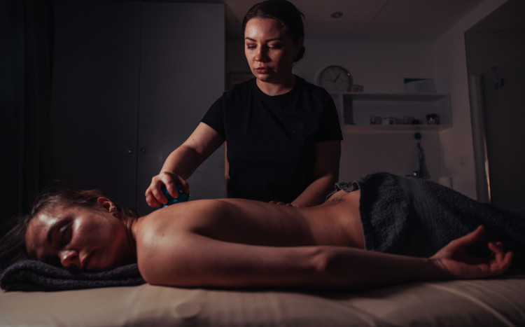 Masażystka wykonująca masaż ujędrniający pleców za pomocą chińskiej bański