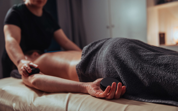 Kobieta leżąca na brzuchu podczas masażu pleców gorącymi kamieniami 