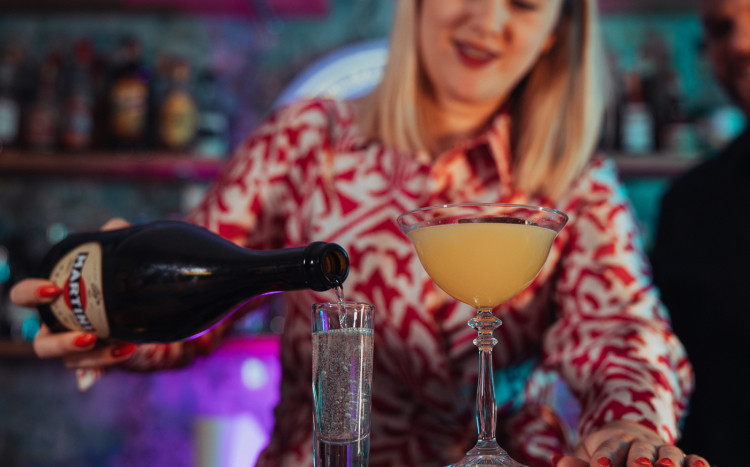 Barmanka wlewająca Martini do wysokiego kieliszka
