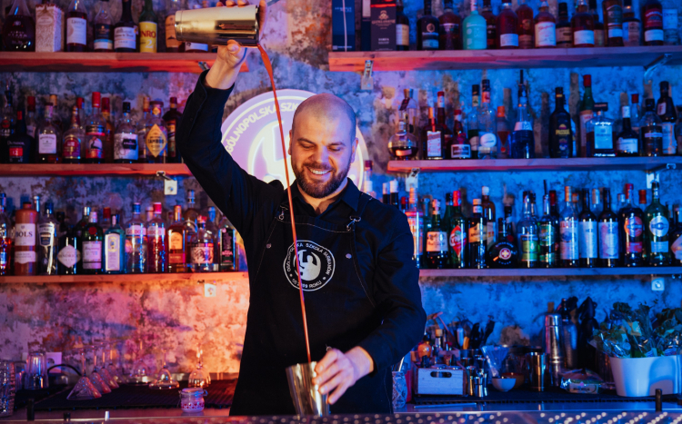 Barman przelewający napój z dwóch części shakera w powietrzu