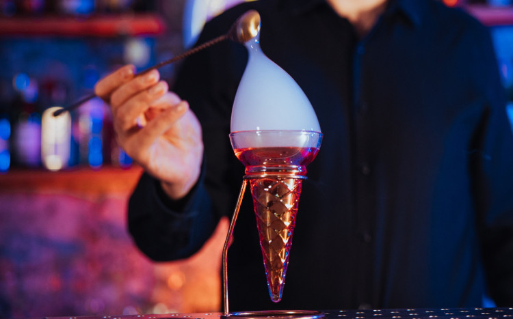 Barman tworzący na drinku bańkę z dymem w środku