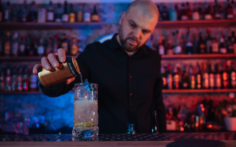 Barman wlewający gazowany napój z puszki do szklanki