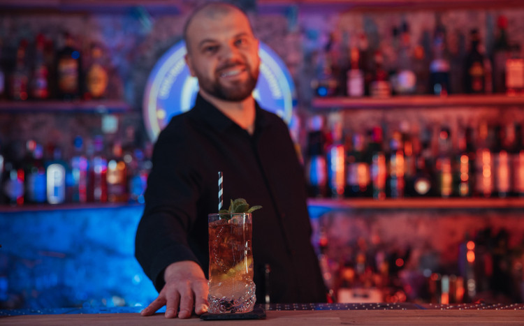 Barman stojący za barem prezentujący gotowy drink