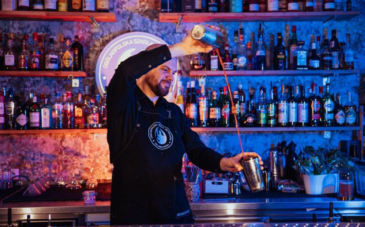 Barman przelewający napój z dwóch części shakera w powietrzu