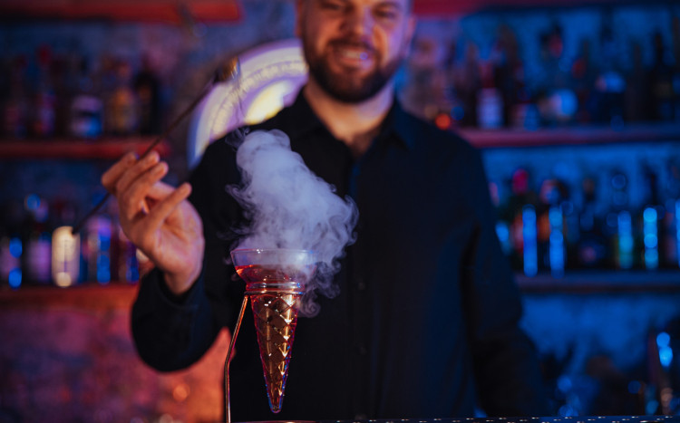 Barman przebijający bańkę z dymem na drinku