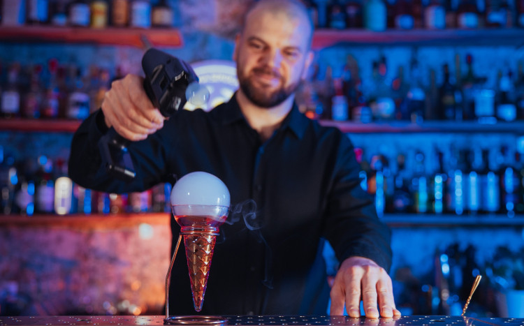 Barman tworzący na drinku bańkę z dymem w środku