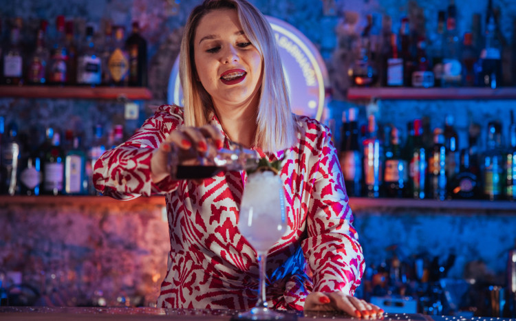 Kobieta barmanka tworząca kolorowego drinka