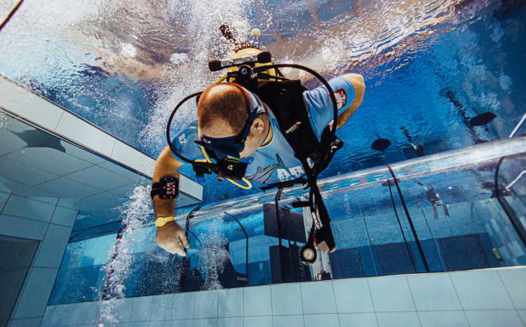 Zdjęcie nurkującego mężczyzny wykonane od dołu w basenie