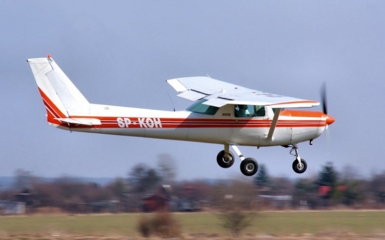 Biało-czerwona Cessna 152 unosząca się nad ziemią