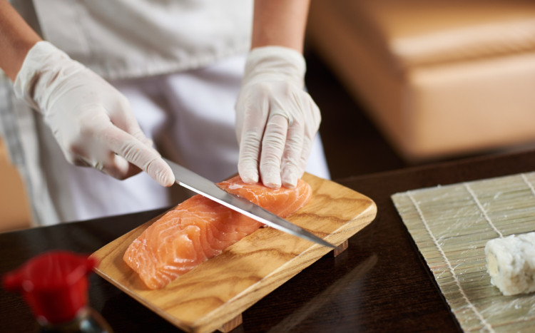 Sushi Master krojący cienkie plastry łososia do sushi