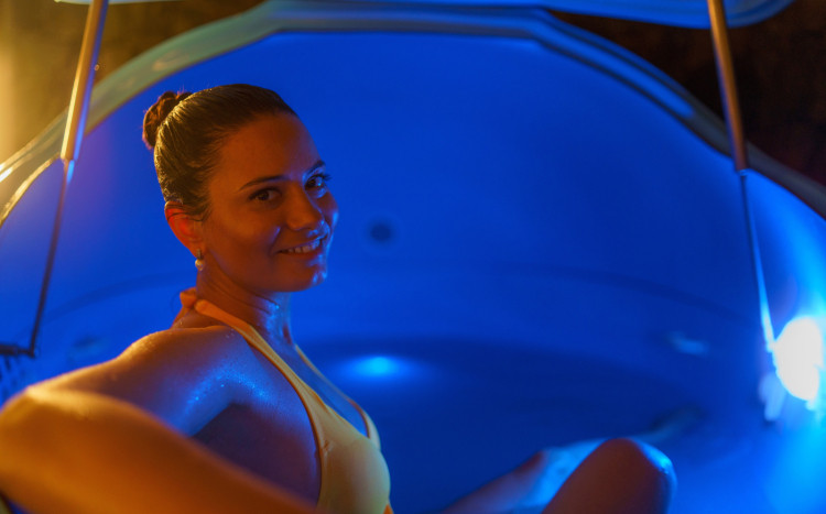 Szczęśliwa kobieta w stroju kąpielowym siedząca w kabinie do floatingu