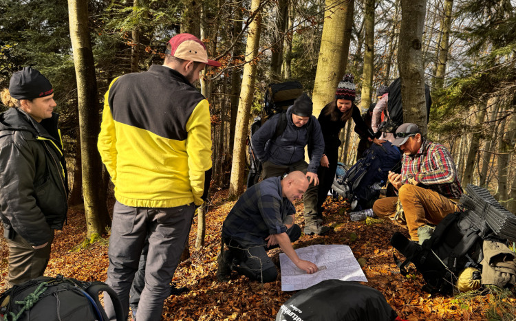 Grupa mężczyzn pracująca nad mapą w lesie