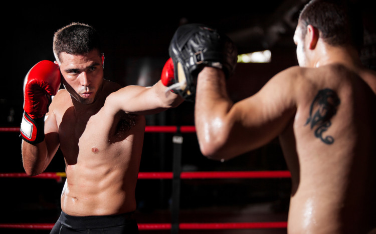 Chłopak bijący się z drugim chłopakiem na ringu w rękawicach bokserskich