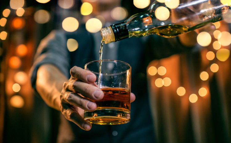 Barman wlewający whisky do szklanki z butelki