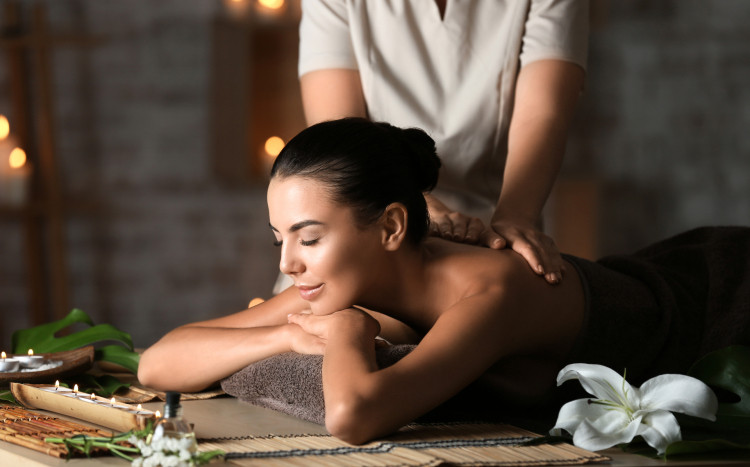 Kobieta leżąca na brzuchu i podpierająca się rękami podczas masażu pleców
