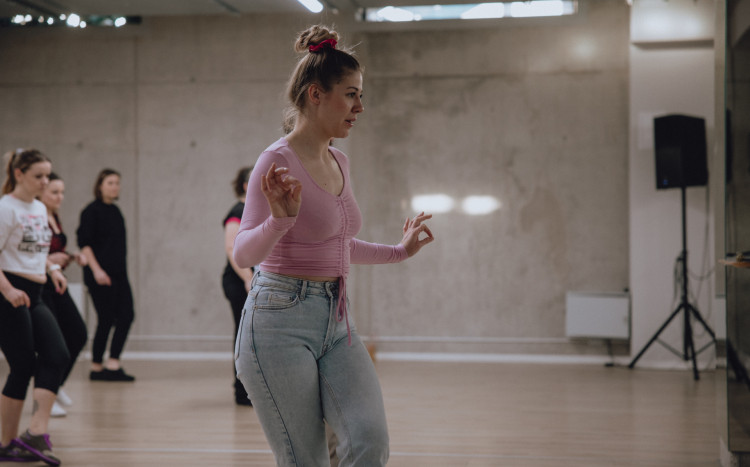 Kobieta w różowej bluzce jako instruktorka tańca