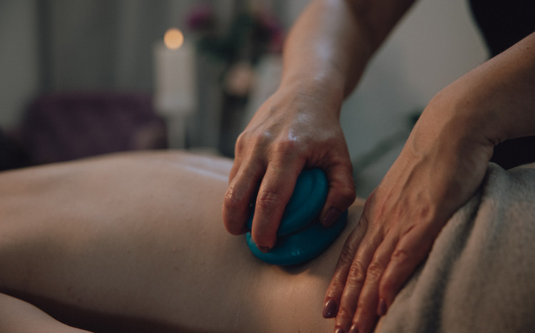 Kobieta masująca plecy niebieską bańką chińską podczas masażu