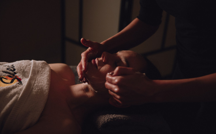 Kobieta podczas masażu twarzy z nakładanym kremem