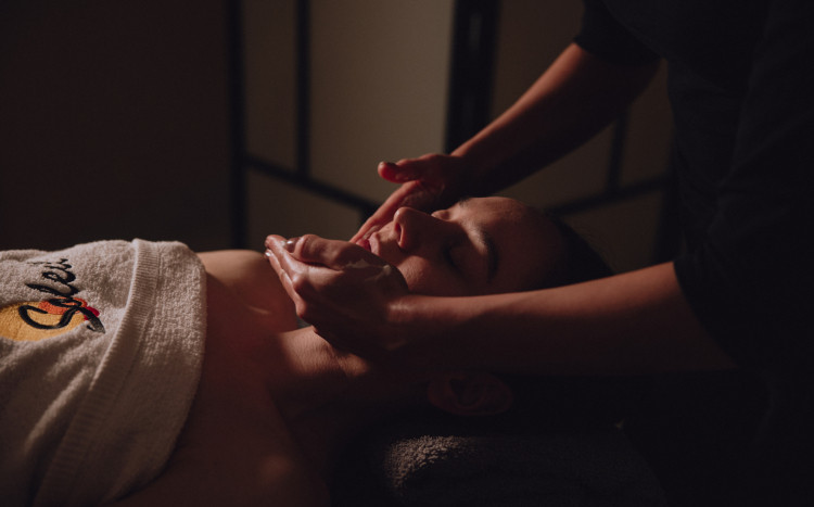 Kobieta podczas masażu twarzy z nakładanym kremem