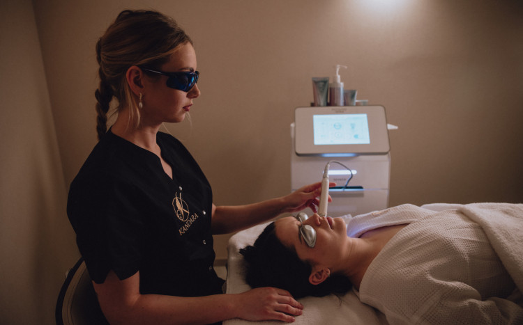 Kosmetolog wykonująca zabieg laserowy na twarzy kobiety