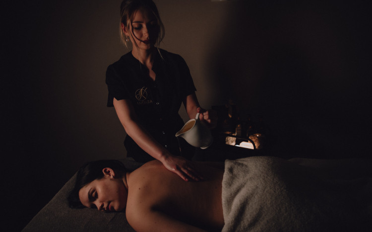 Kobieta wylewająca ciepły wosk podczas masażu świecą na swoją rękę 