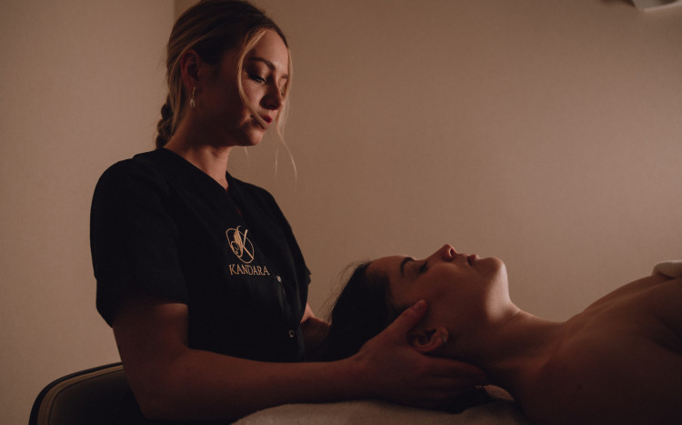 Masażystka wykonująca odprężający masaż karku i twarzy u kobiety