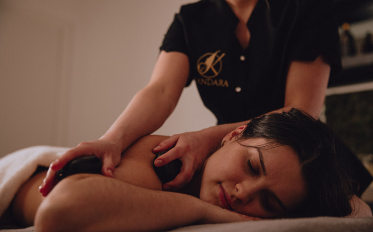 Kobieta leżąca na brzuchu podczas masażu pleców gorącymi kamieniami 