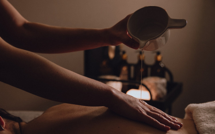 Masażystka polewająca ciepły olejek do masażu na swoją rękę 