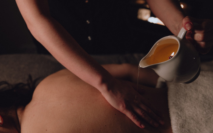 Masażystka wylewająca ciepły wosk podczas masażu świecą na swoją rękę 