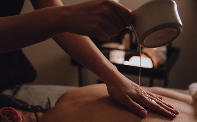 Masażystka polewająca ciepły olejek do masażu na swoją rękę 
