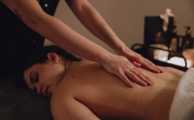 Dłonie masażystki masujące plecy kobiety leżącej na brzuchu