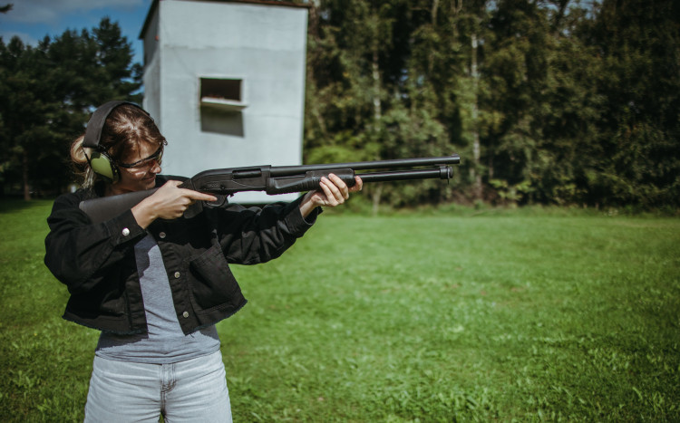 Kobieta przygotowująca się do oddania strzelnego strzału na odkrytej strzelnicy